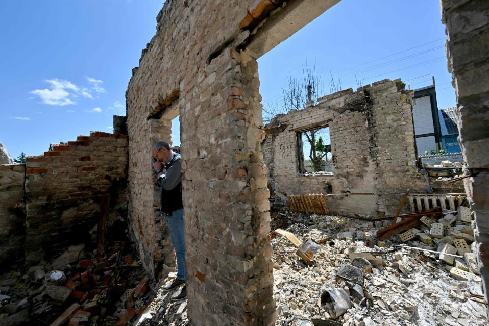 75-vuotias mies katsoo tuhoutuneen talon raunioita.