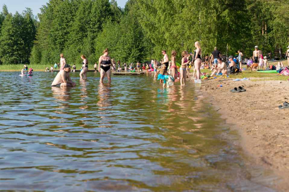 Paljon ihmisiä Tuomiojärven uimarannalla aurinkoisena kesäpäivänä.