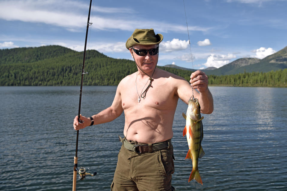 Vladimir Putin ilman paitaa ottaa aurinkoa rannalla.