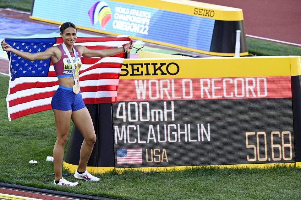 Maailmanennätyksen juossut Sydney McLaughlin Yhdysvaltojen lipun kanssa tulostaulun vieressä.