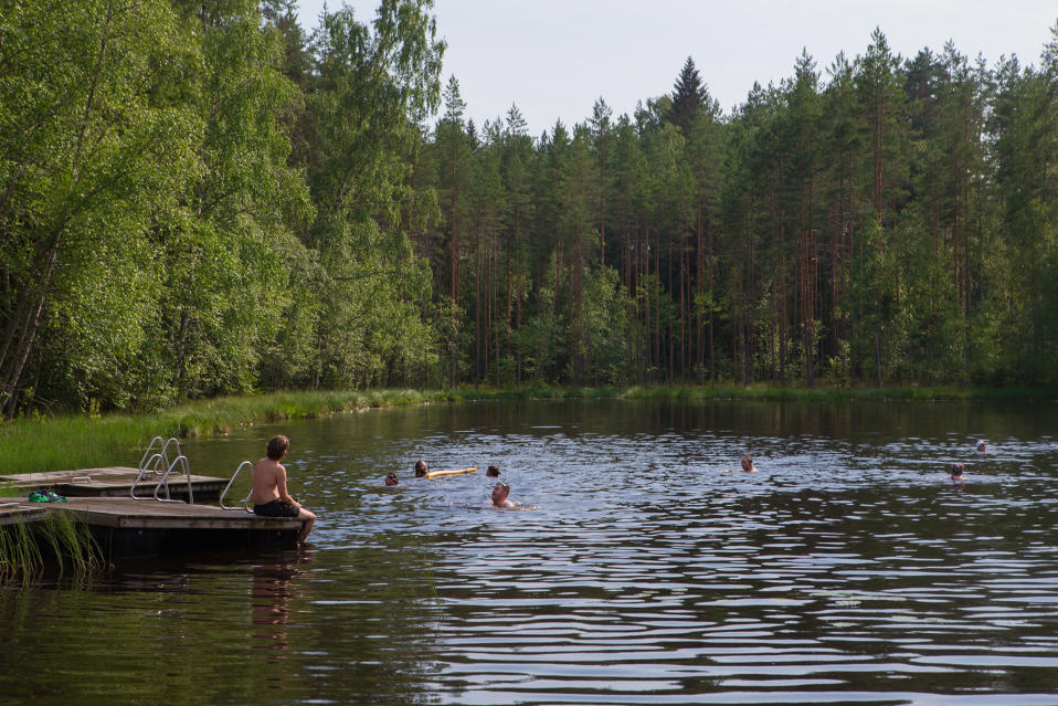 Ihmisiä uimassa metsälammessa