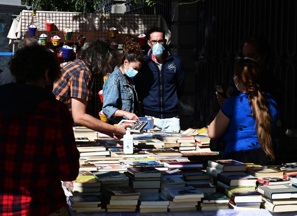Turistit katselevat kirjoja kirpputorilla maskit päässään.
