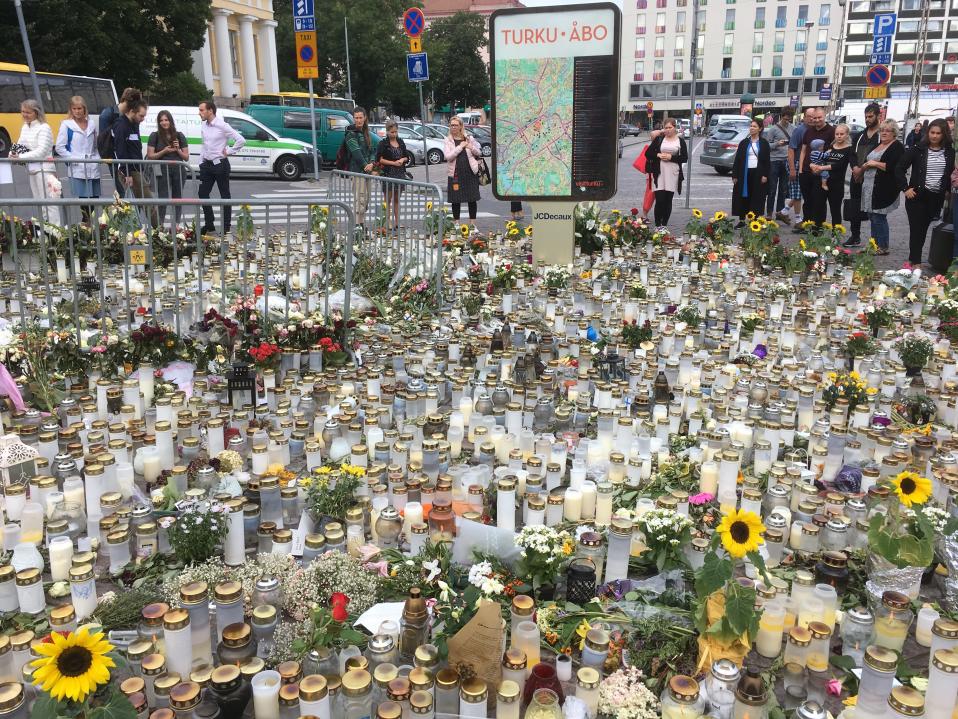 Människor står tysta kring ljus- och blomsterhavet efter knivdådet på Åbo salutorg den 18 augusti 2017.