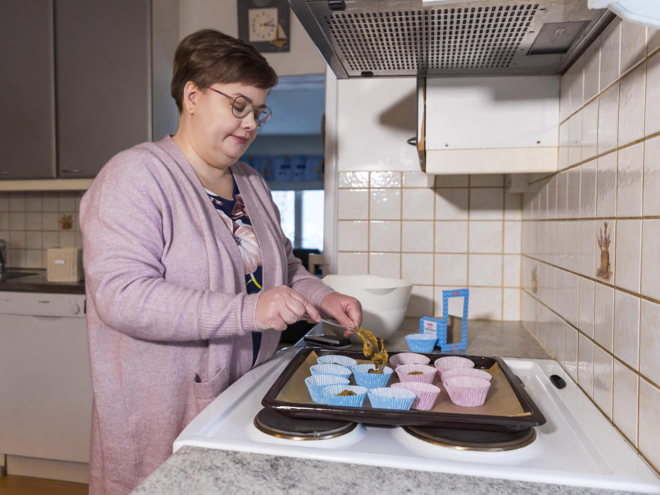 Heidi Hyytiäinen täyttää muffinssivuokia taikinalla hellan ääressä.