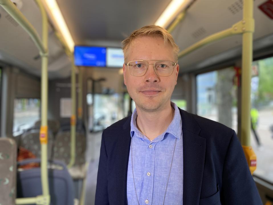 Nyssen suunnittelupäällikkö Juha-Pekka Häyrynen seisoo bussissa päällään sininen paita ja tummansininen takki. 