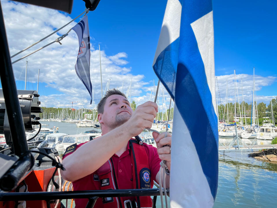 Espoon Meripelastajien päivystävä päällikkö Markus Nikander nostaa Suomen lipun liehumaan veneessä.