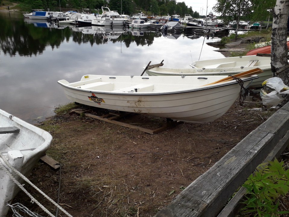 Valkoinen soutuvene, jonka kyljessä on ruskeita tahroja.