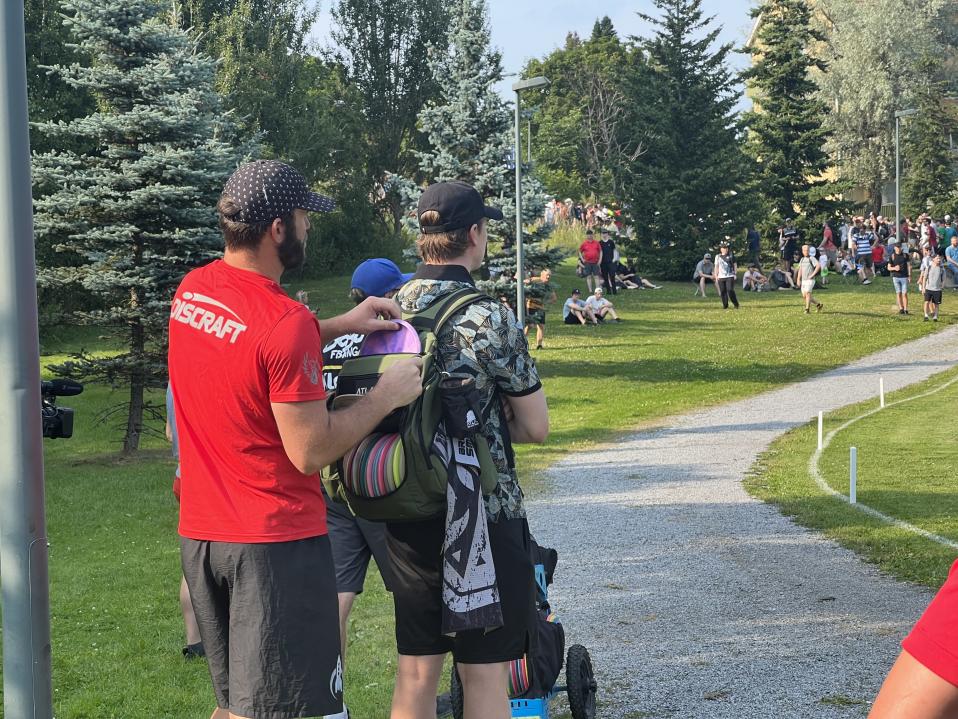 Brodie Smith (left) switches out his disc after consulting with his caddy (right). 