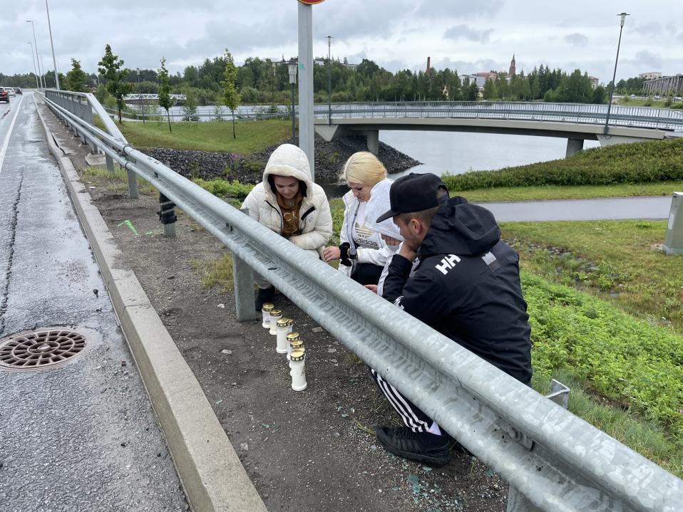 Ihmiset laskevat muistokynttilöitä tien varteen.