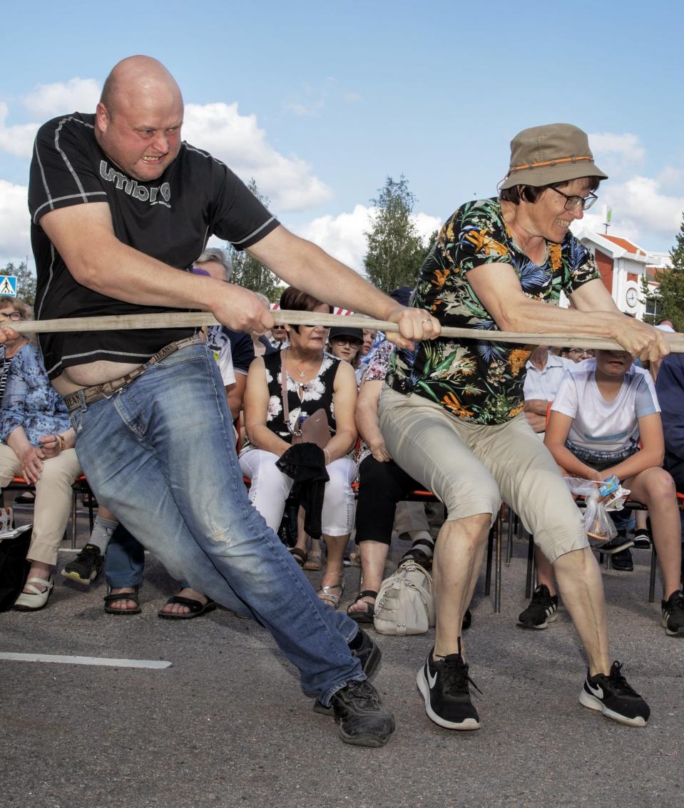 Nainen ja mies vetävät köyttä samalla puolella. Kovat irvistykset.