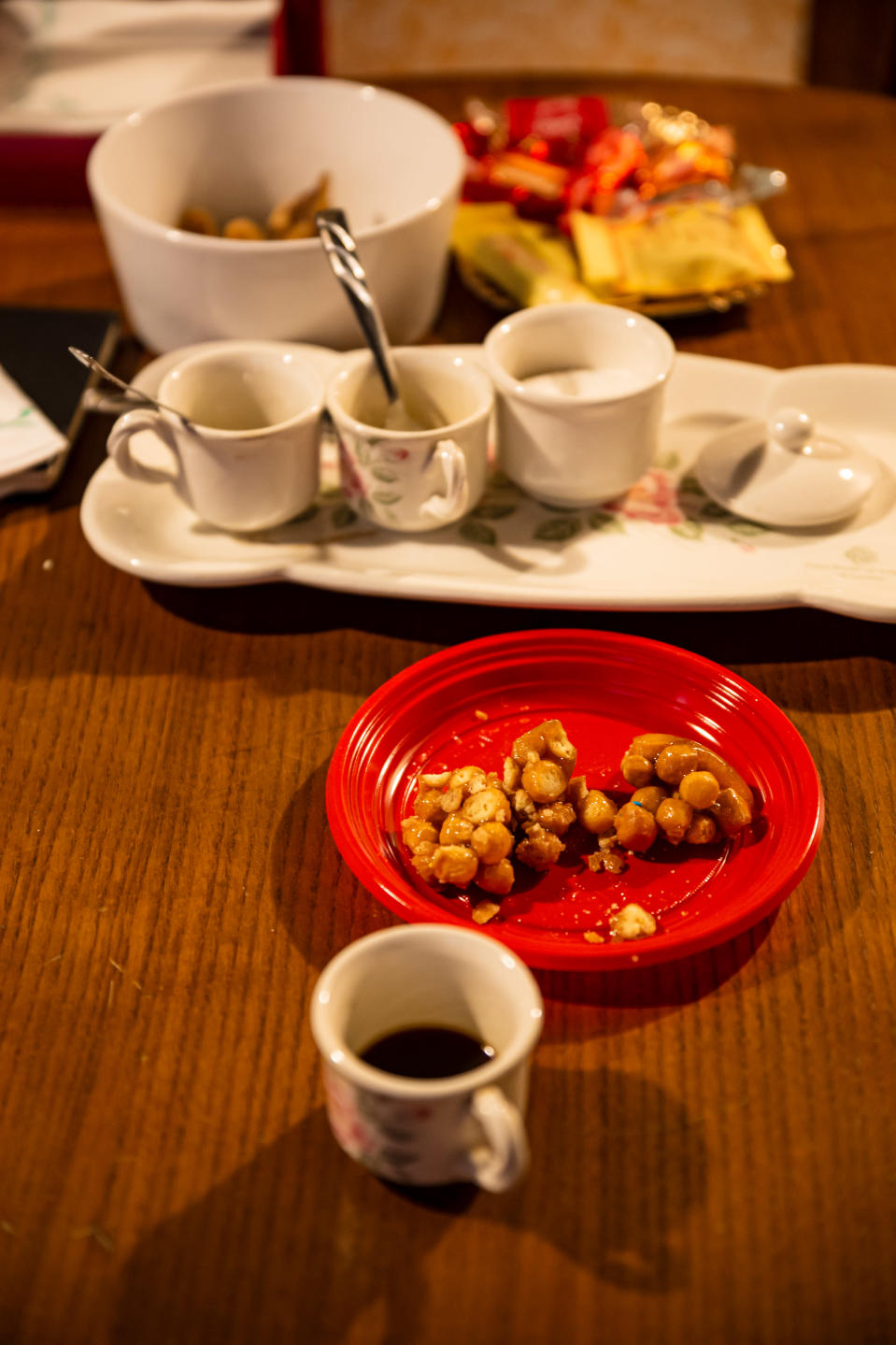 Pöydällä näkyy pieniä espresso-kahvikuppeja sekä lautasella naposteltavaa, ilmeisesti manteleita tai joitakin pähkinöitä.