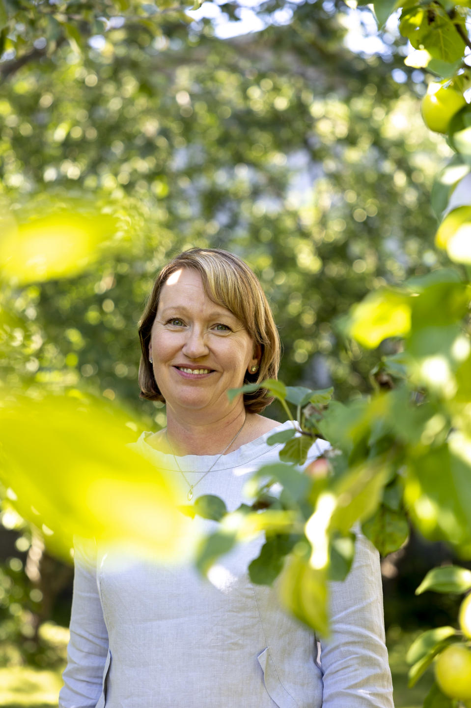 Kristiina Koivula seisoo omenapuiden välissä.