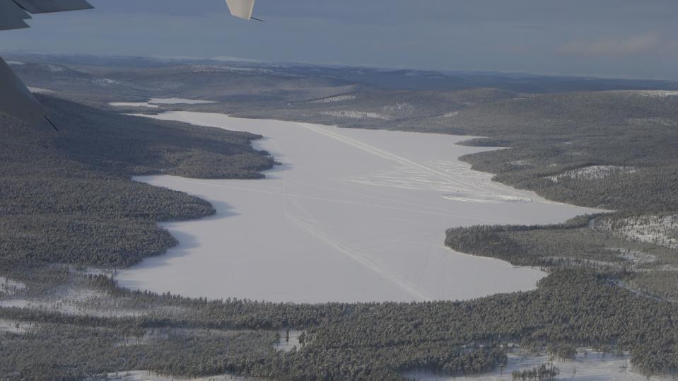 Pasasjärvi ilmakuvassa talvella. Jäällä näkyy jälkiä ajoneuvoissa. 