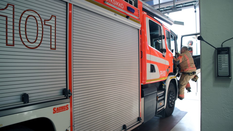 Palomies kiipeää paloautoon.