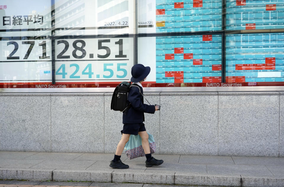 Pieni koululainen kulkee pörssi mainoksen ohi kadulla Tokiossa.