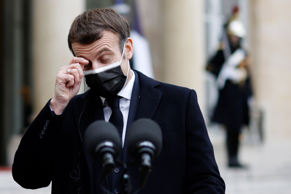 Kasvomaskiin pukeutunut Emmanuel Macron hieroo silmäänsä tiedotustilaisuudessa.