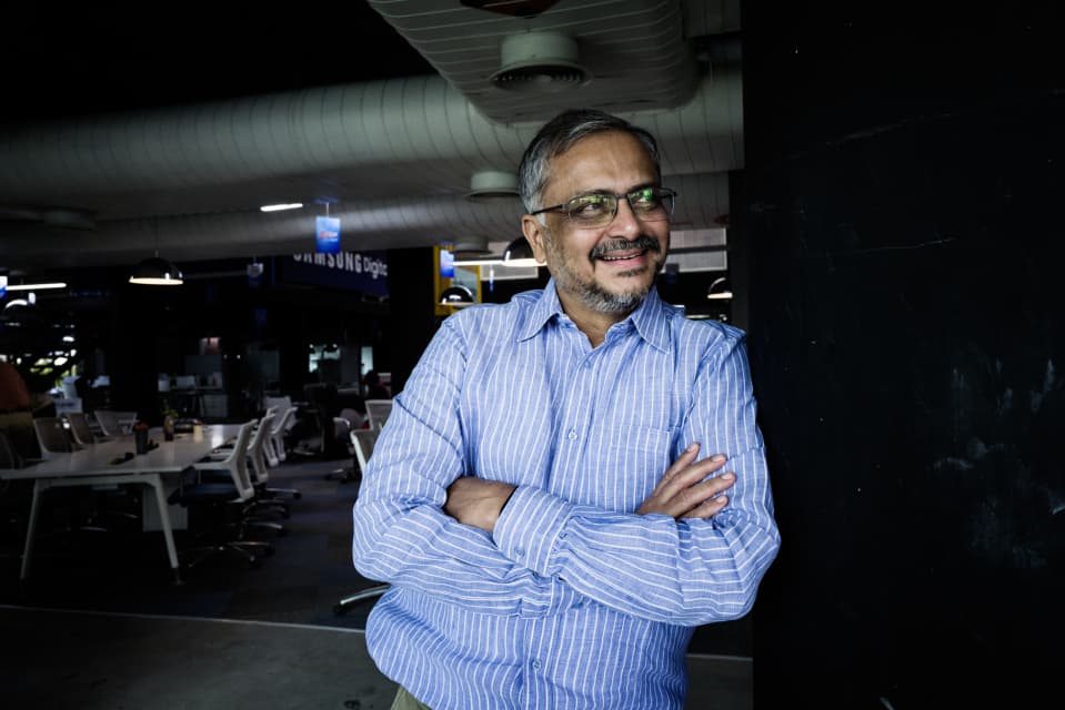 Ravi Narayan hymyilee ja nojaa T-Hubin toimiston seinään kädet puuskassa.