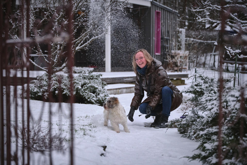 Tiina Peltola leikkii koiransa kanssa puutarhassaan.