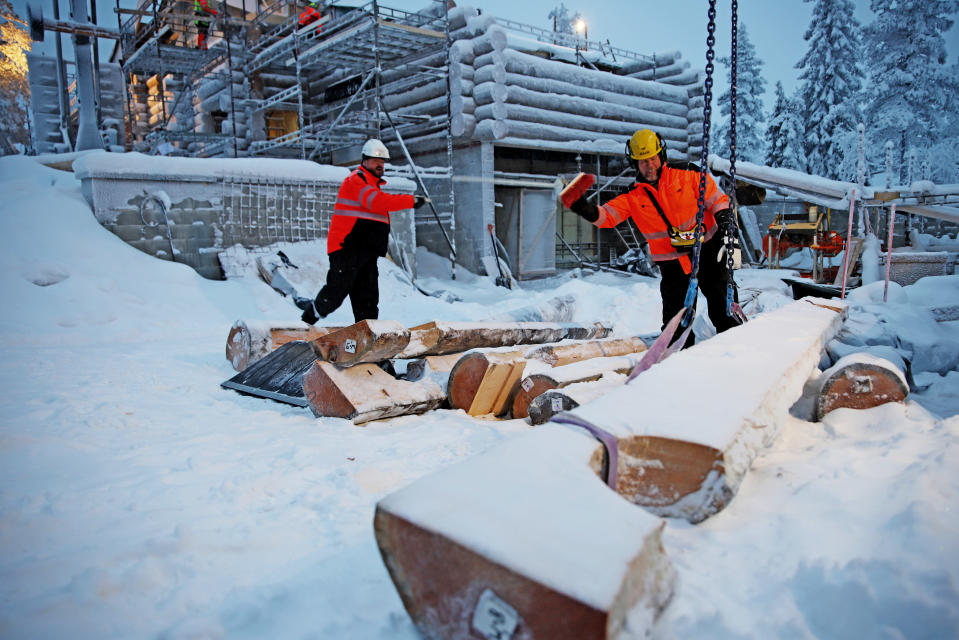 Työmiehet sahaavat hirsiä Levillä.