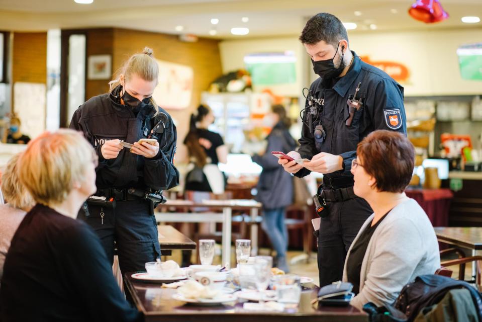 Poliisit tarkastavat koronapasseja ruokailijoilta ravintolassa.