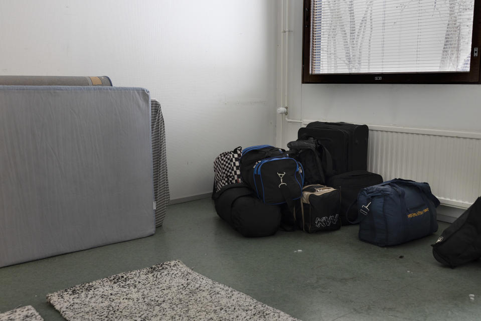 On the floor of the room are the bags of the newly arrived refugees in the living room of the Salmiranta reception center.  There are two carpets on the floor and the changed mattresses lean against the wall. 