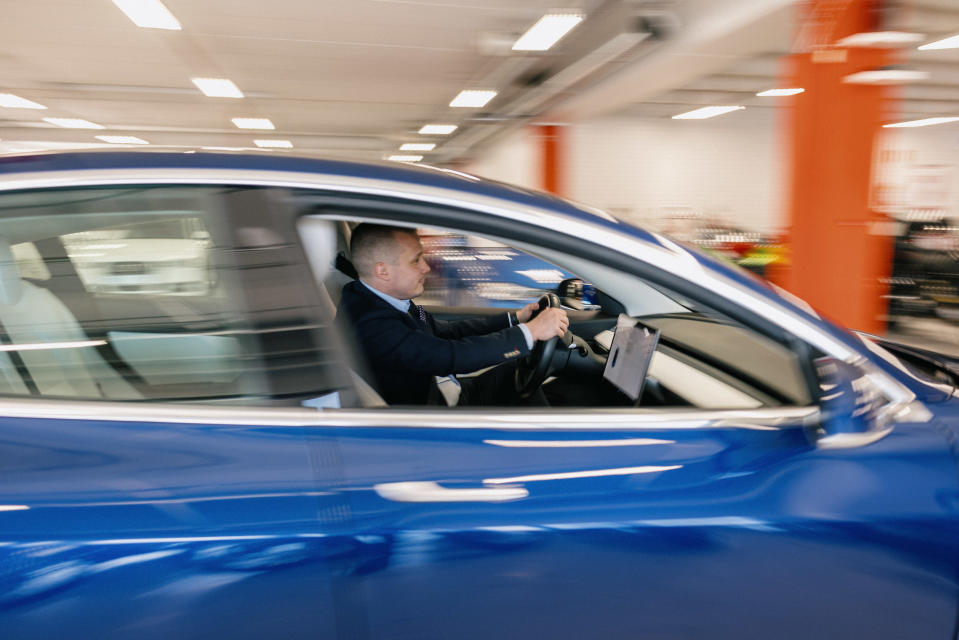 Autoliikkeen ostojohtaja Pietro Jääskeläinen siirtää Tesla sähköautoa liiketilasta ulos koeajoa varten.