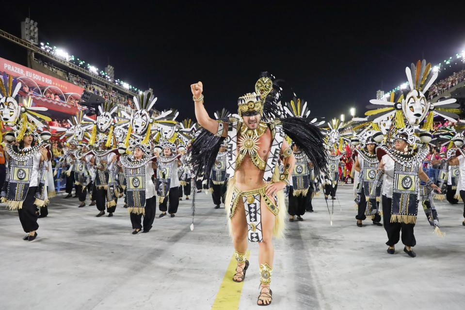 Suuri ryhmä tanssijoita Rion karnevaaleissa pukeutuneina mustaan, valkoiseen ja kultaan.