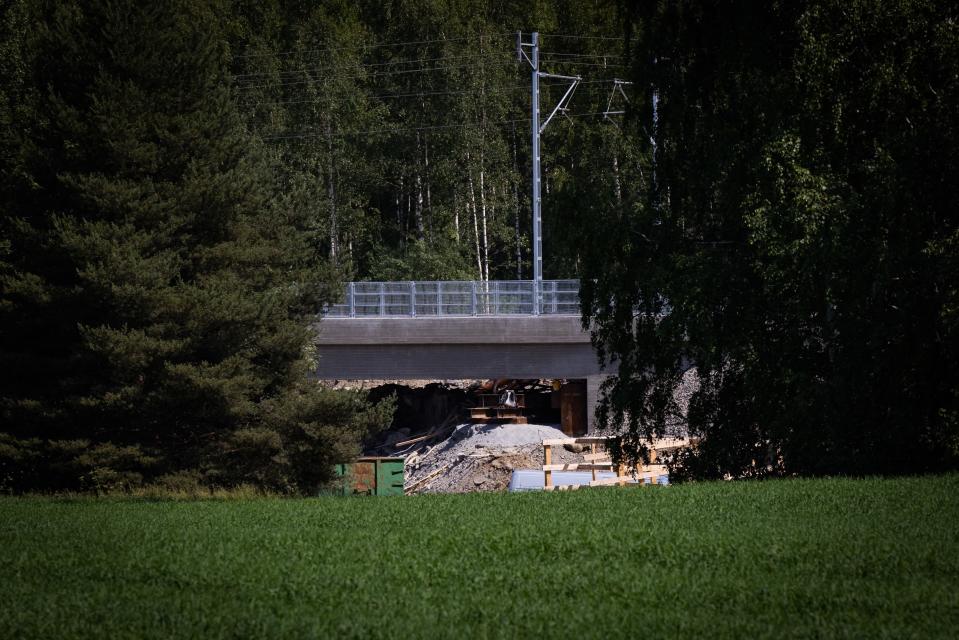 Vihreän pellon takaa otettu kuva vanhan sillan purkutyömaasta.