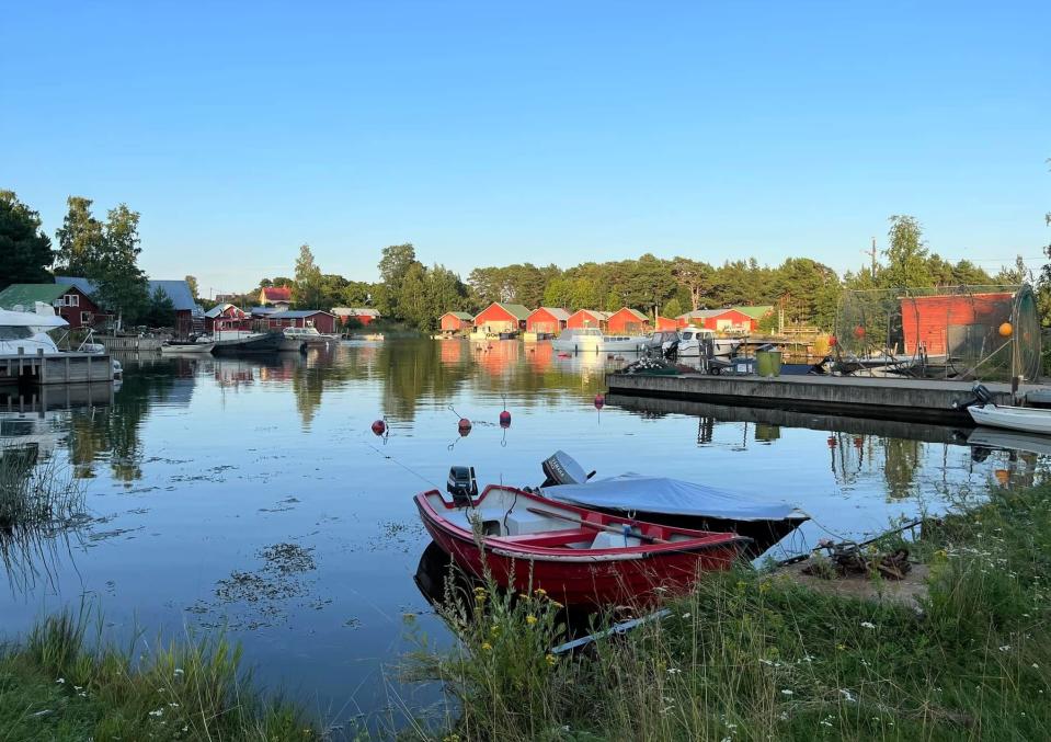 Vene ja saaristomaisemaa punaisena rakennuksineen kauniina kesäpäivänä.