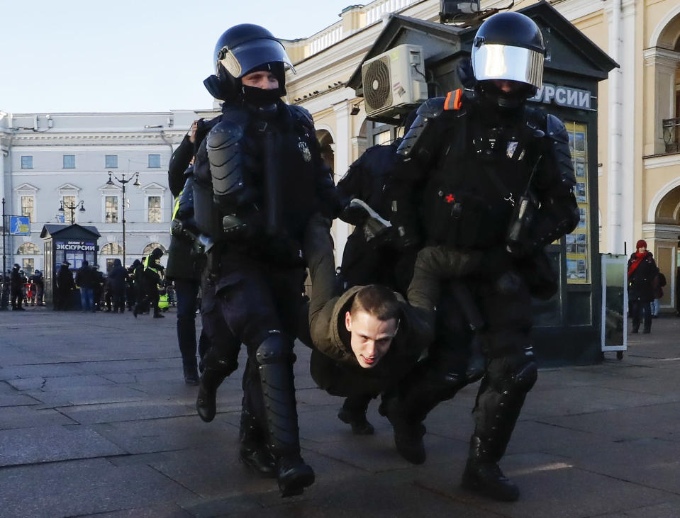 Raskaasti suojatuneet poliisit kantavat mielenosoittajaa käsistä ja jaloista.