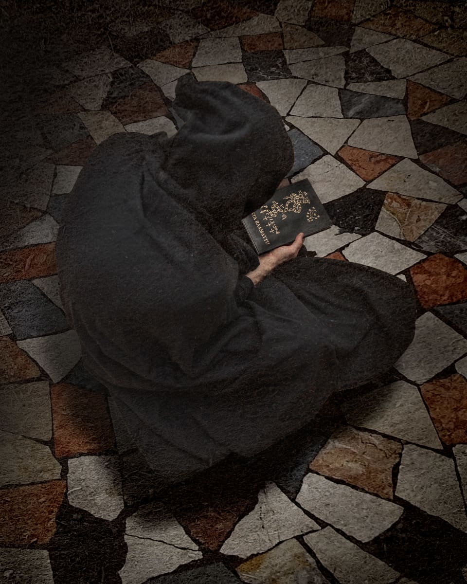 "Saatananpalvoja" kaavussa musta raamattu kädessä.