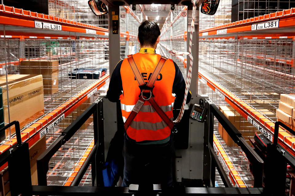 Työntekijä hyllyjen välissä Amazonin uudessa jakelukeskuksessa Wernessä, Saksassa.