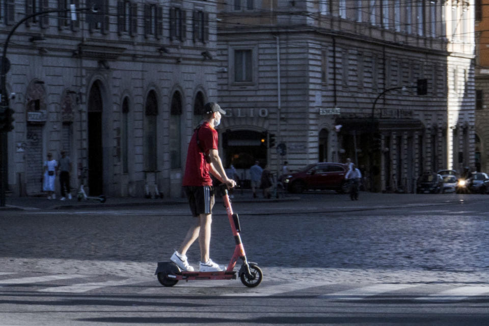 A person on an electric kickboard on a Roman street.