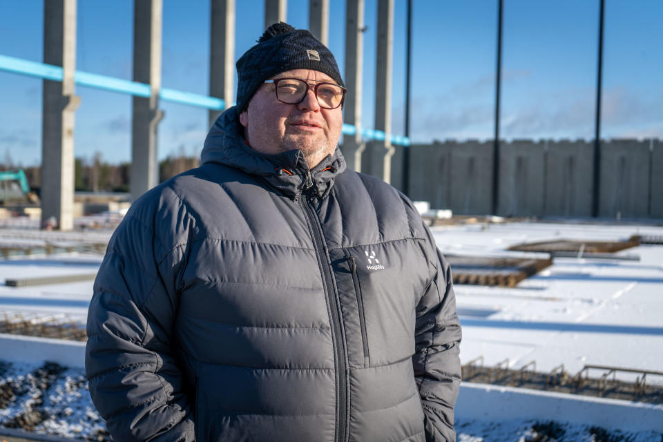 Vesa Ojala, Karhu Basketin puheenjohtaja, seisoo aurinkoisella rakennustyömaalla talvivaatteissa.