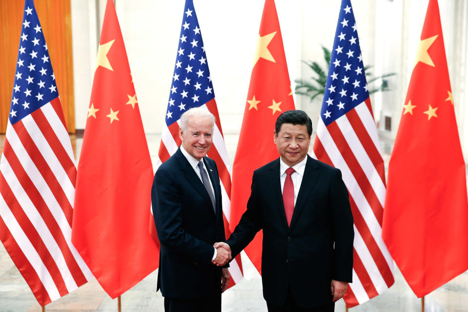 Joe Biden och Xi Jinping skakar hand. I bakgrunden USA:s och Kinas flagga.