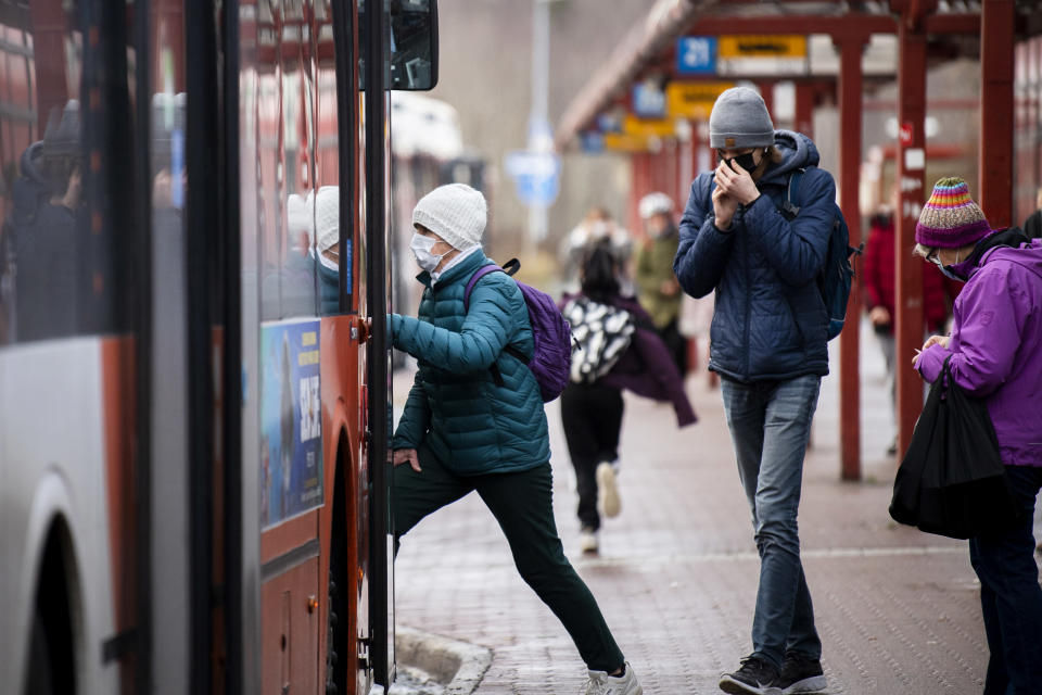 Kasvomaskiin pukeutunut henkilö nousee bussin kyytiin.