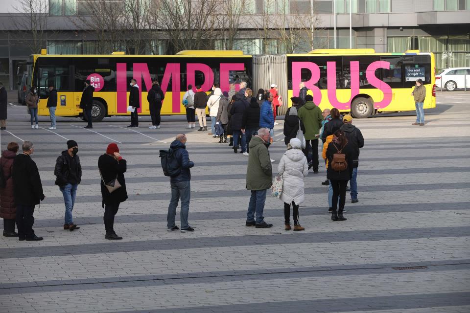 Ihmisiä jonottamassa rokotusbussiin.