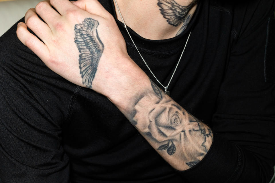 A black shirted person with tattoos on his hand and neck.