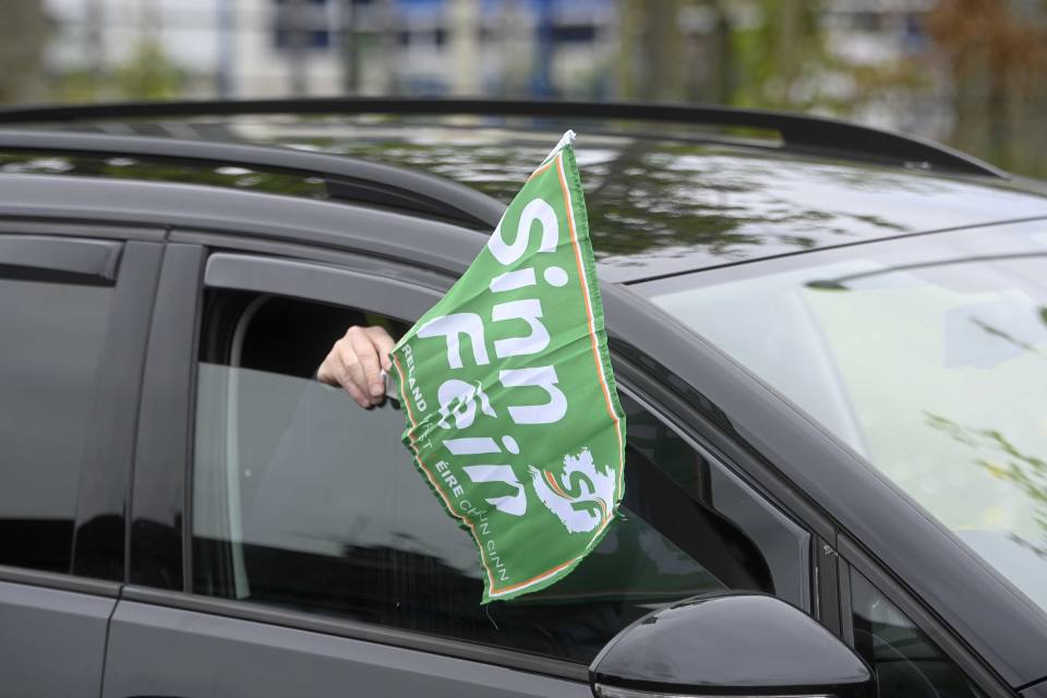 Sinn Feinin lippua auton ikkunasta pitelevä käsi.
