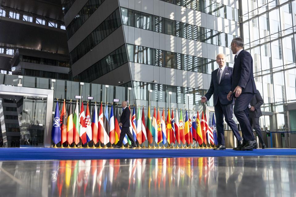 Yhdysvaltain presidentti Joe Biden ja Naton pääsihteeri kävelevät Nato-jäsenmaiden lippurivistön edessä Naton-huippukokouksessa maaliskuussa 2022.