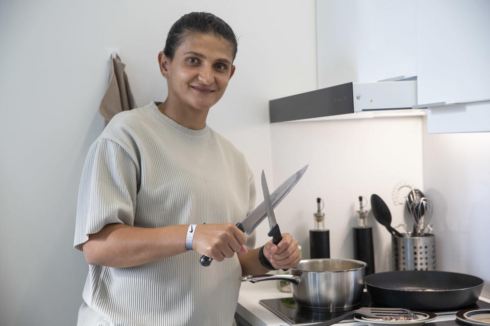 Jalkapalloilija Lavdije Begolli keittiön lieden ääressä, veitset käsissään.