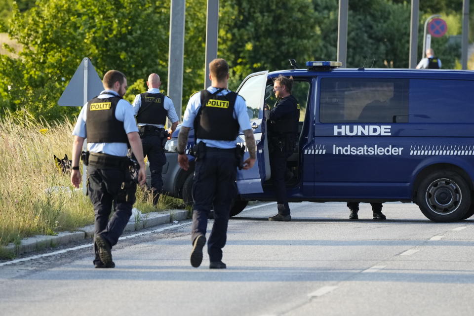 Kaksi poliisia kävelee kohti poliisiautoa, joka on pysäköity autotien keskelle poikkisuunnassa. 