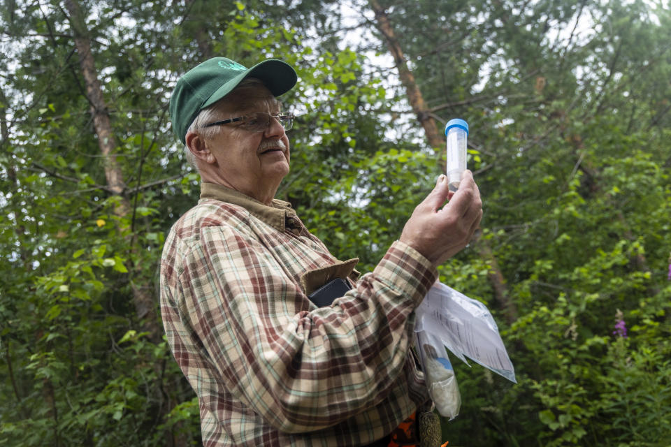 Kalevi Koponen pitää käsissään putkiloa, jossa on karhun kakkaa.