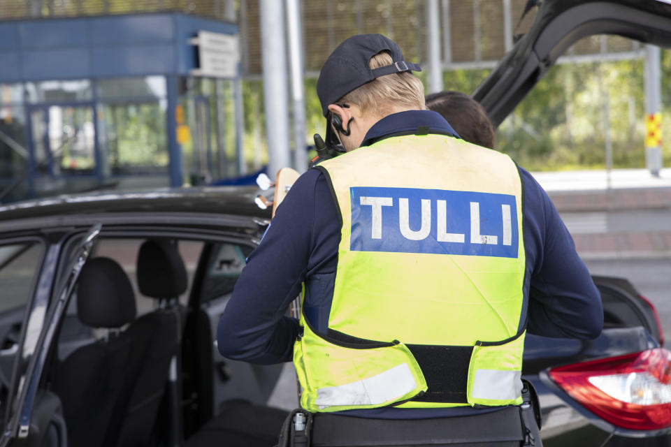 Tullimies tutkii Venäjälle menevän matkustajan papereita Niiralan raja-asemalla. 