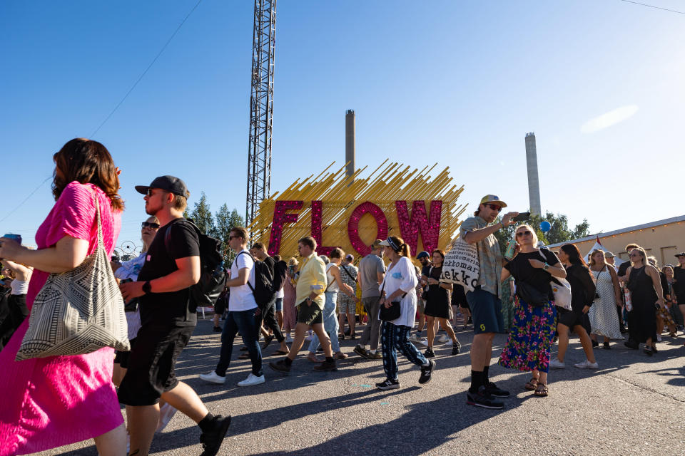 Flow-festvaalin flow-kyltti, jonka edestä kulkee lukuisa joukko ihmisiä.