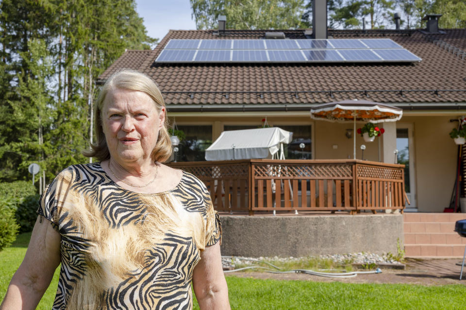 Nainen seisoo talon takapihalla. Taustalla näkyy aurinkopaneelit talon katolla.